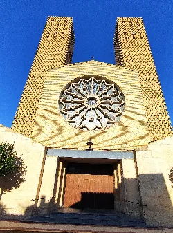 Facade of the church with a large rose window and brick side towers.