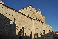 Iglesia y murallas de Fuentes de Valdepero bajo un cielo azul.