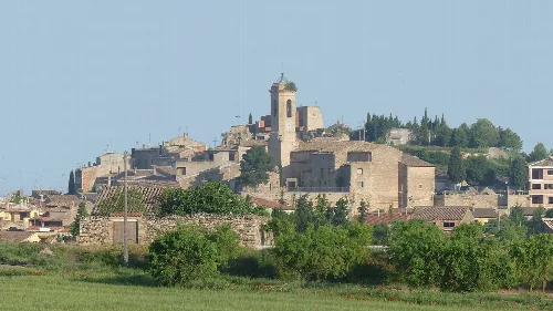 Blick auf ein Dorf auf einem Hügel mit Kirche und Häusern.