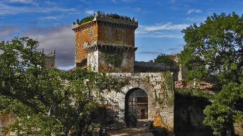 Schloss Pambre mit Turm und Mauern in einer grünen Umgebung unter blauem Himmel.