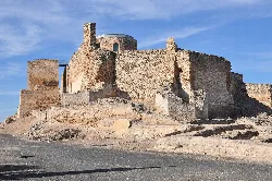 Ruinas de un castillo de piedra con torre redonda y muros en Carrión de Calatrava.