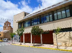 Modern town hall building of Ribaforada with trees and an old church in the background.