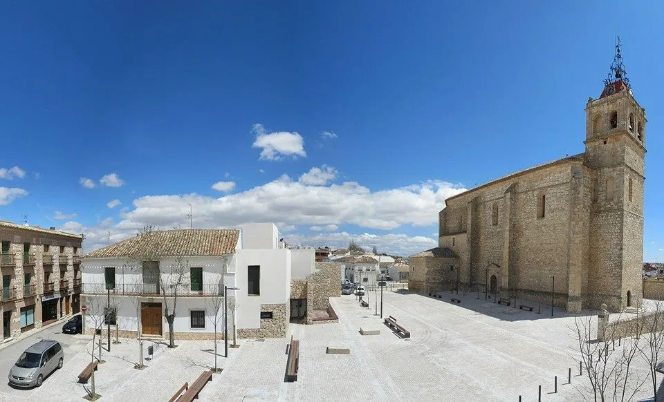 Cerrillo Square with benches, trees, and an old church in Horcajo de Santiago.