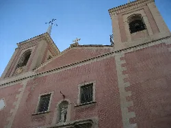 Vista de la iglesia con dos torres y una estatua en la entrada.