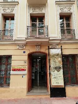Entrance to the museum with glass door and informational sign on the sidewalk.