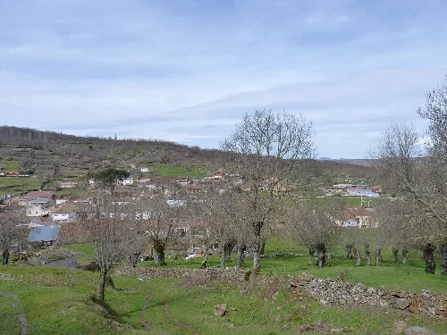 Paisaje rural con casas, árboles y un cielo azul en La Calzada de Béjar.