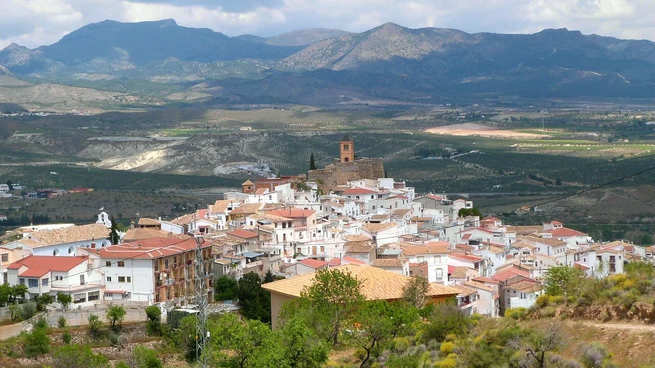 Vista de un pueblo con casas blancas en un valle rodeado de montañas.