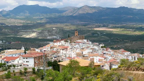 Vista de un pueblo con casas blancas en un valle rodeado de montañas.