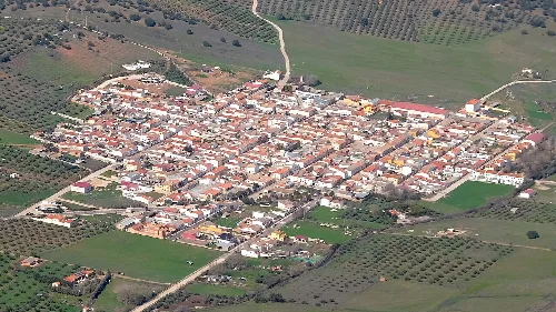 Luftaufnahme eines Dorfes mit geraden Straßen und weißen Gebäuden in ländlicher Umgebung.
