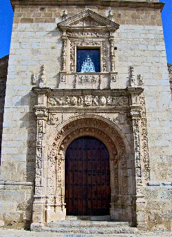 Stone facade with wooden door and plateresque decoration.