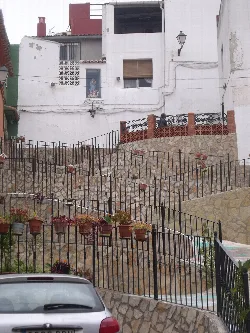 Escalinata con plantas en macetas y casas blancas en Chella.