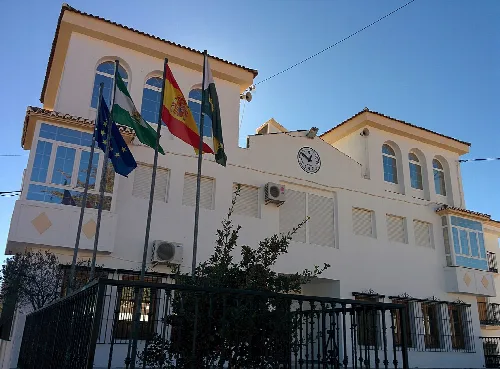 Weißes Gebäude mit Flaggen und Uhr an der Fassade.