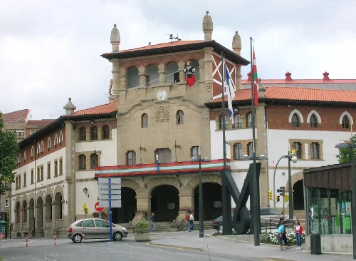 Edificio del ayuntamiento de Mungia con banderas y estructura de piedra.