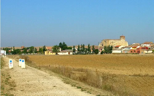 Landscape with field and village, and an old church in the distance.