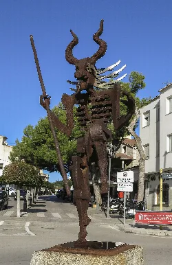 Escultura de un demonio con cuernos y bastón en una plaza de Artá.