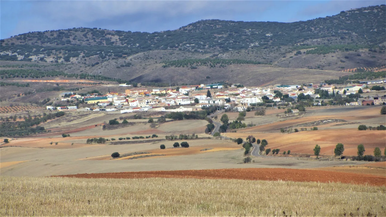 Landschaft mit Dorf und Bergen im Hintergrund.