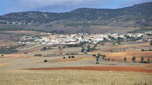 Landschaft mit Dorf und Bergen im Hintergrund.