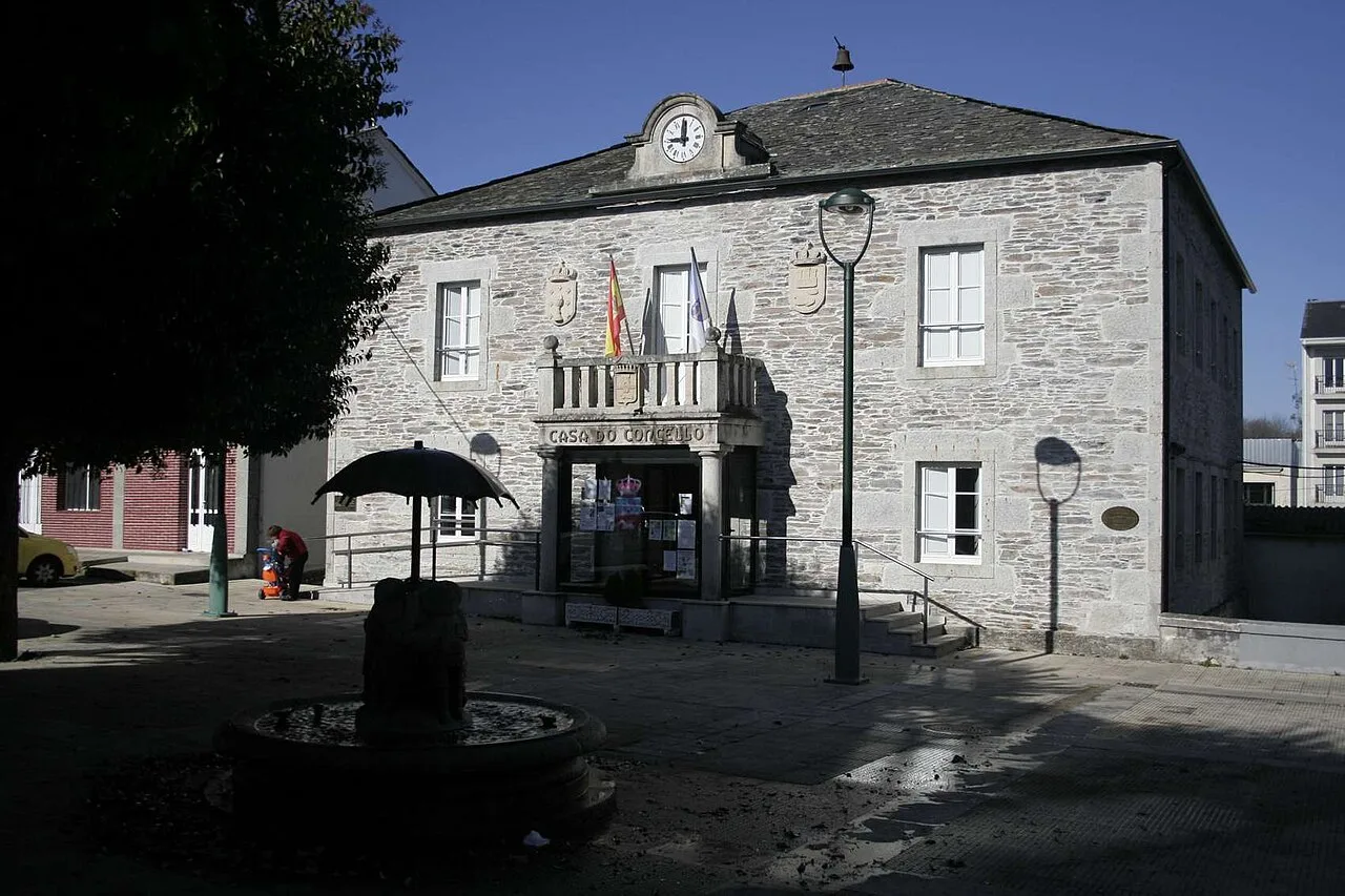 Stone building with clock and flags on the facade of the Town Hall.