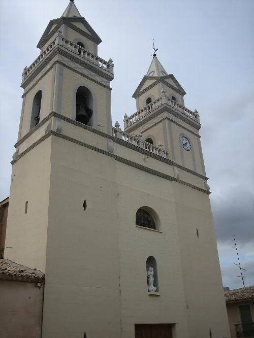 Church with two towers and a clock, cloudy sky.