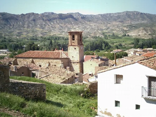 Church of the Assumption with mountains and rooftops in Aguilar del Río Alhama.