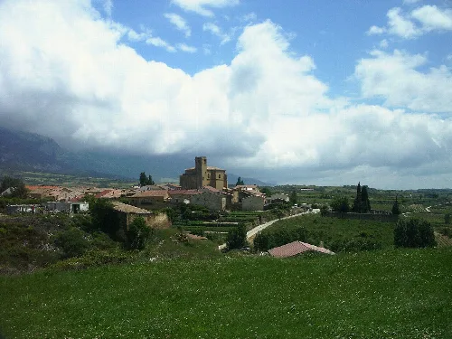 Blick auf Samaniego mit Kirche und Häusern in einer grünen, bergigen Landschaft.