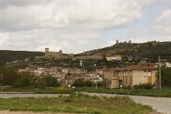 Blick auf eine Stadt mit Burgruinen auf dem Hügel und modernen Häusern im Vordergrund.