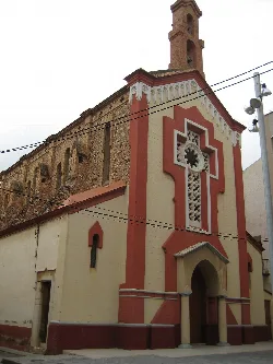 Facade of a church with red and beige details in Benicarló.