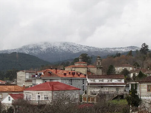 Häuser und Gebäude in Entrimo mit schneebedeckten Bergen im Hintergrund.