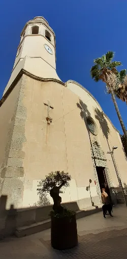 Facade of a church with tower and palm trees in Premià de Mar.