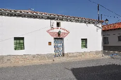 White house with decorated door and green barred windows in Villaflor.