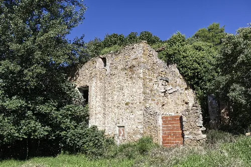 Restos de un molino de piedra en Caudiel, con paredes de piedra y vegetación.