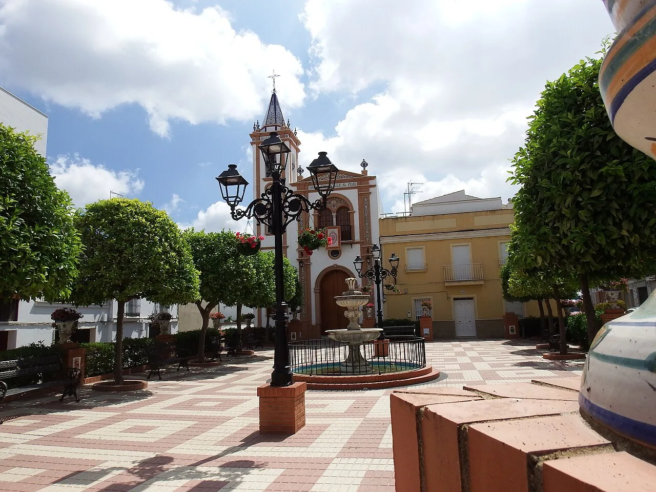 Square with trees, lampposts, and fountain in Bonares.