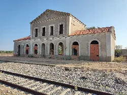 Edificio de estación de tren con arcos y ventanas, junto a las vías.