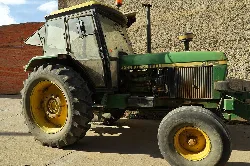 Green tractor with cab and large wheels in a yard.