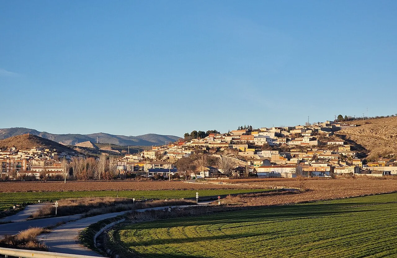 Landscape of Pinos Puente with hillside houses and fields in the foreground.
