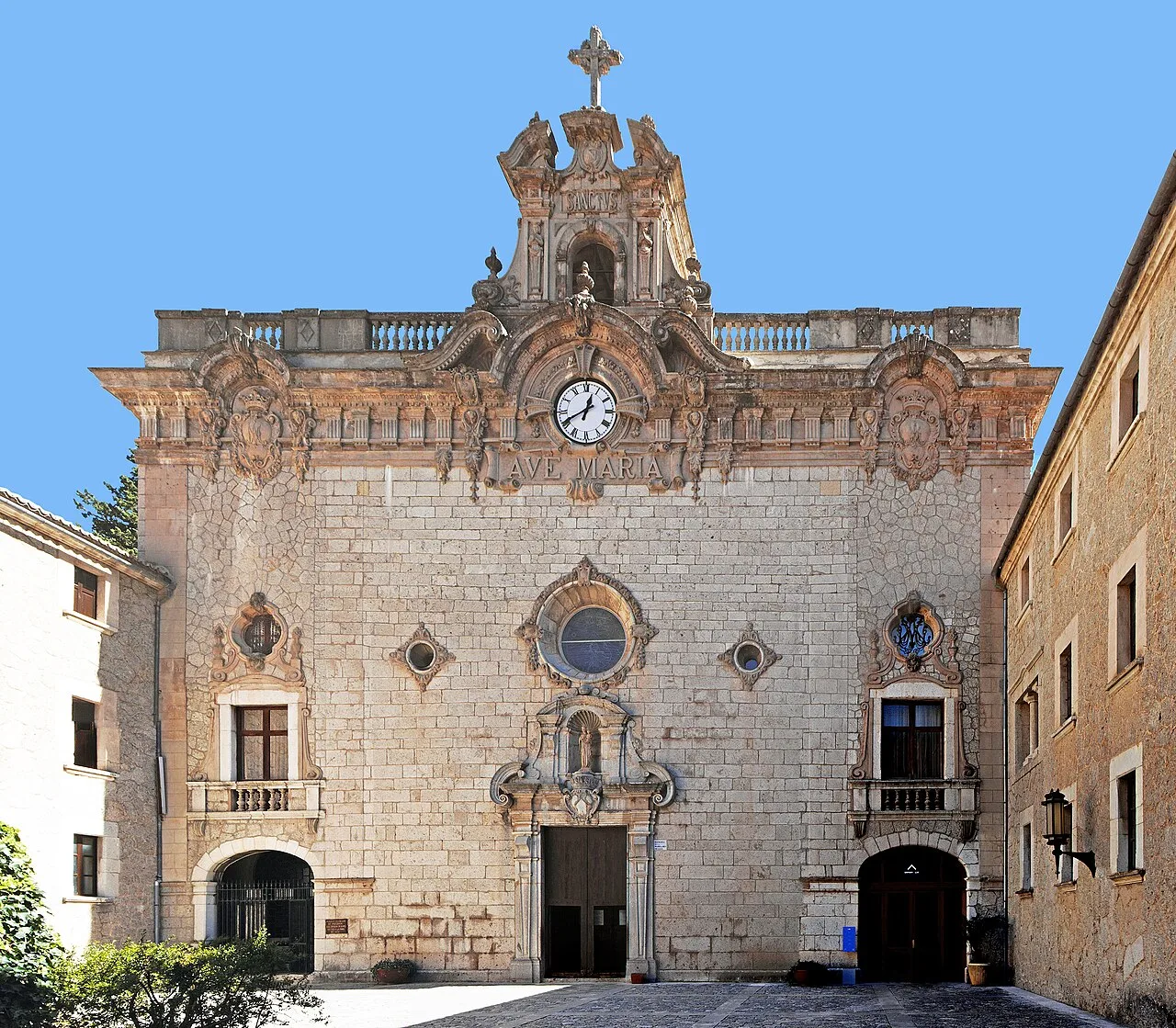 Fachada de una iglesia con reloj y cruz en la parte superior.