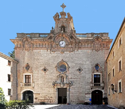 Facade of a church with clock and cross at the top.
