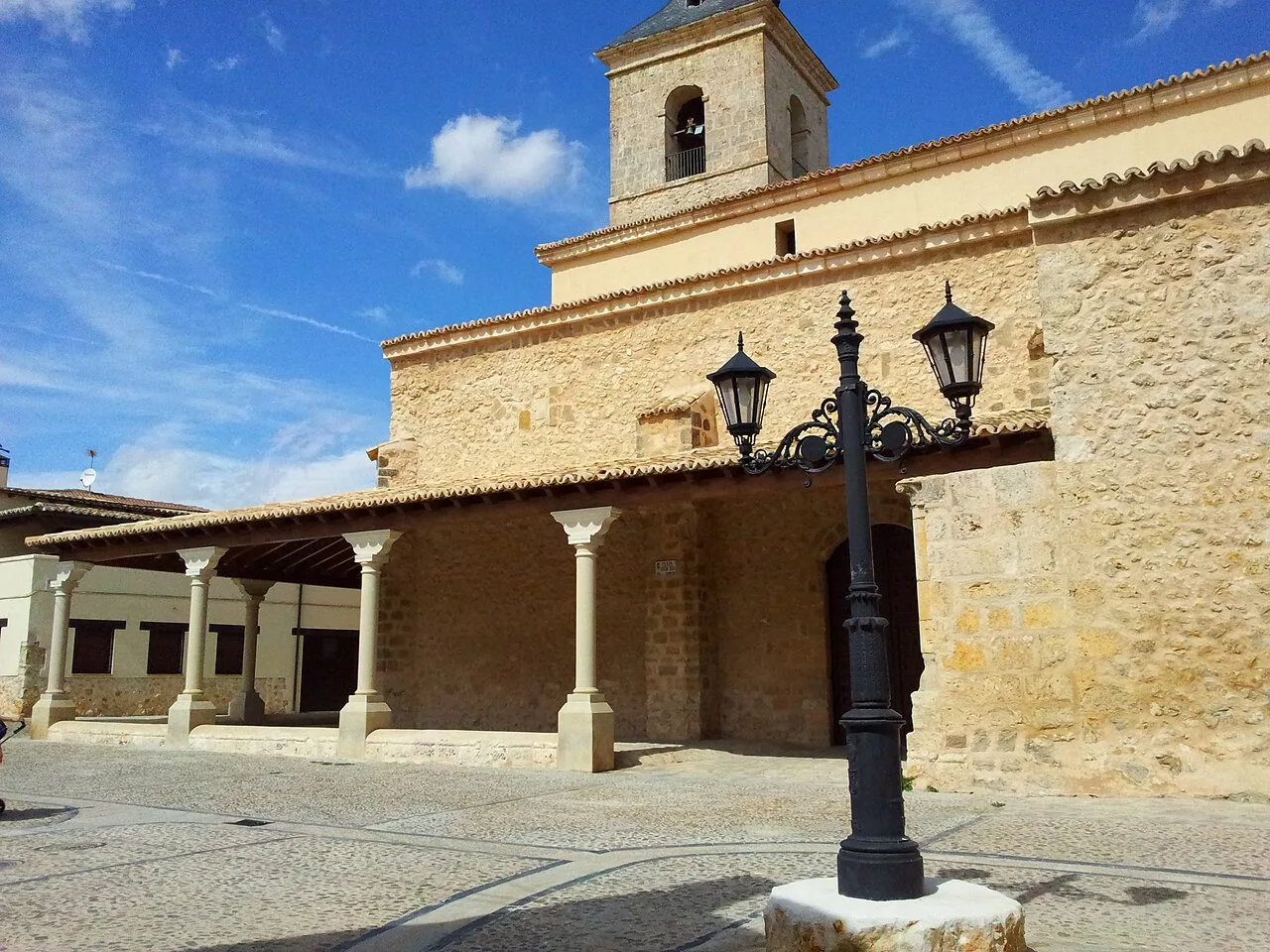 Stone church with tower and facade in Fuentelencina under a blue sky.
