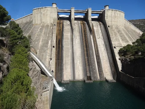 Große Betonkonstruktion mit Wasser am Boden und Vegetation an den Seiten.