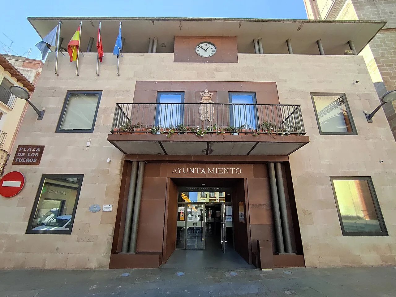 Town hall building with flags and clock on the facade.