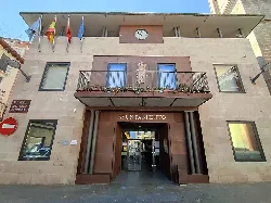 Town hall building with flags and clock on the facade.