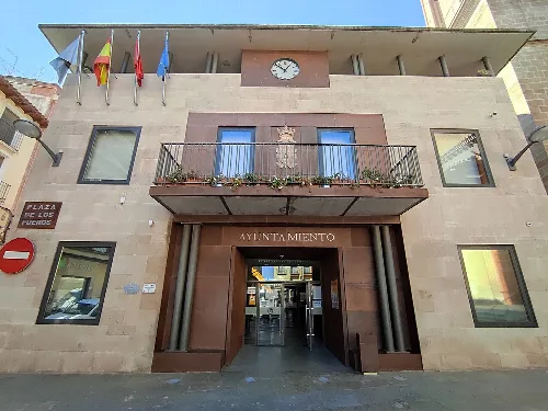 Edificio del ayuntamiento con banderas y reloj en la fachada.