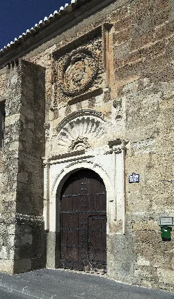 Puerta de una iglesia con detalles escultóricos y un buzón de esperanza a la derecha.