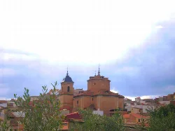 Iglesia de Santa Quiteria en Elche de la Sierra con nubes en el cielo.