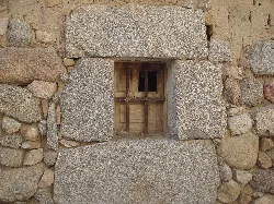 Wooden small window in stone wall in La Torre, Ávila.