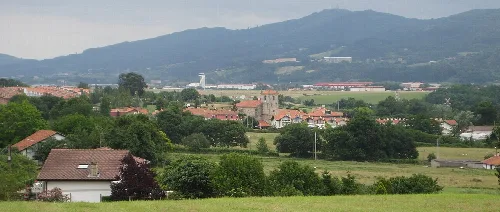 Paisaje con casas, árboles y la torre de control del aeropuerto de Bilbao en Loiu.
