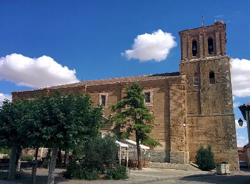 Iglesia del Salvador con torre y árboles en Herrín de Campos.