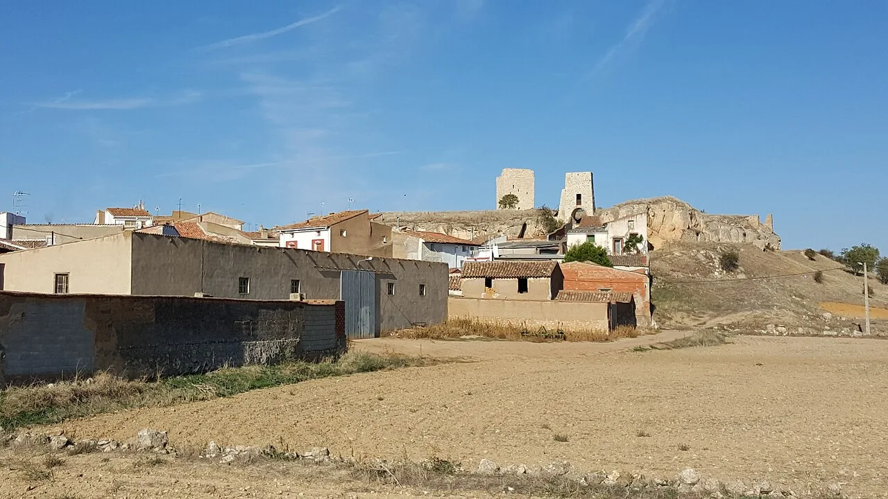 View of a village with a castle on the hill and rural buildings.