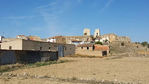 View of a village with a castle on the hill and rural buildings.