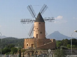 Molino de viento en Santa Ponça, Mallorca, con montañas al fondo.